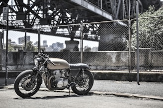 brown standard motorcycle near wire fence during daytime