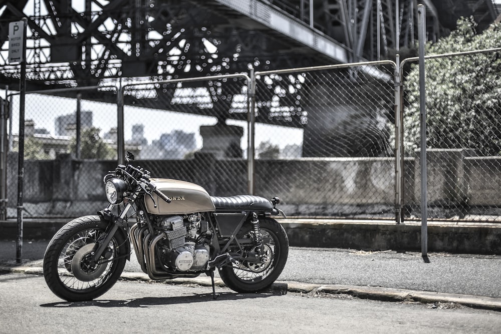 brown standard motorcycle near wire fence during daytime