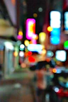 A bustling city street at night, alive with colorful neon signs and blurred motion.