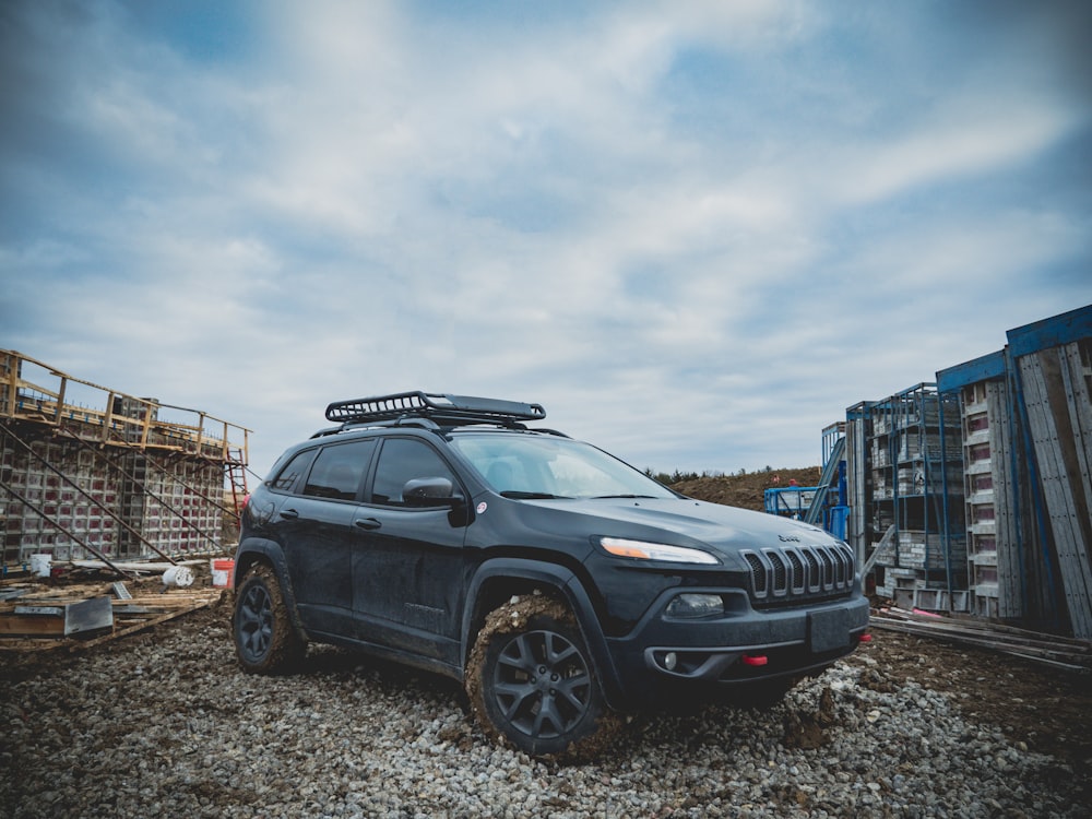 black Jeep Cherokee SUV parked on gravel ground