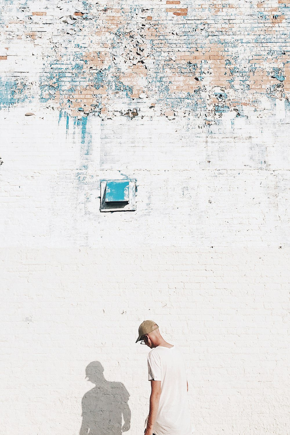 man standing facing white brick wall