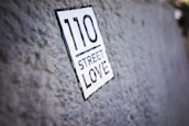 A close-up of a textured surface with a sticker that reads '110 Street Love.' The focus is on the sticker while the background is slightly blurred.