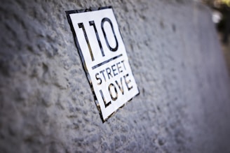 A close-up of a textured surface with a sticker that reads '110 Street Love.' The focus is on the sticker while the background is slightly blurred.