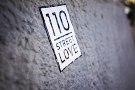 A close-up of a textured surface with a sticker that reads '110 Street Love.' The focus is on the sticker while the background is slightly blurred.