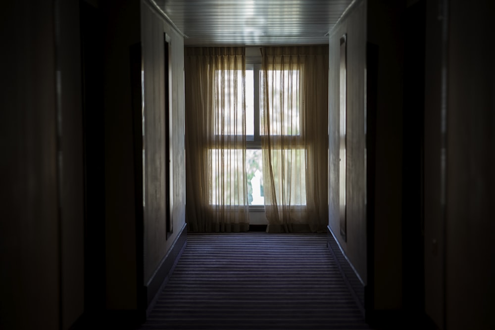 hallway leading to window covered by brown window curtain