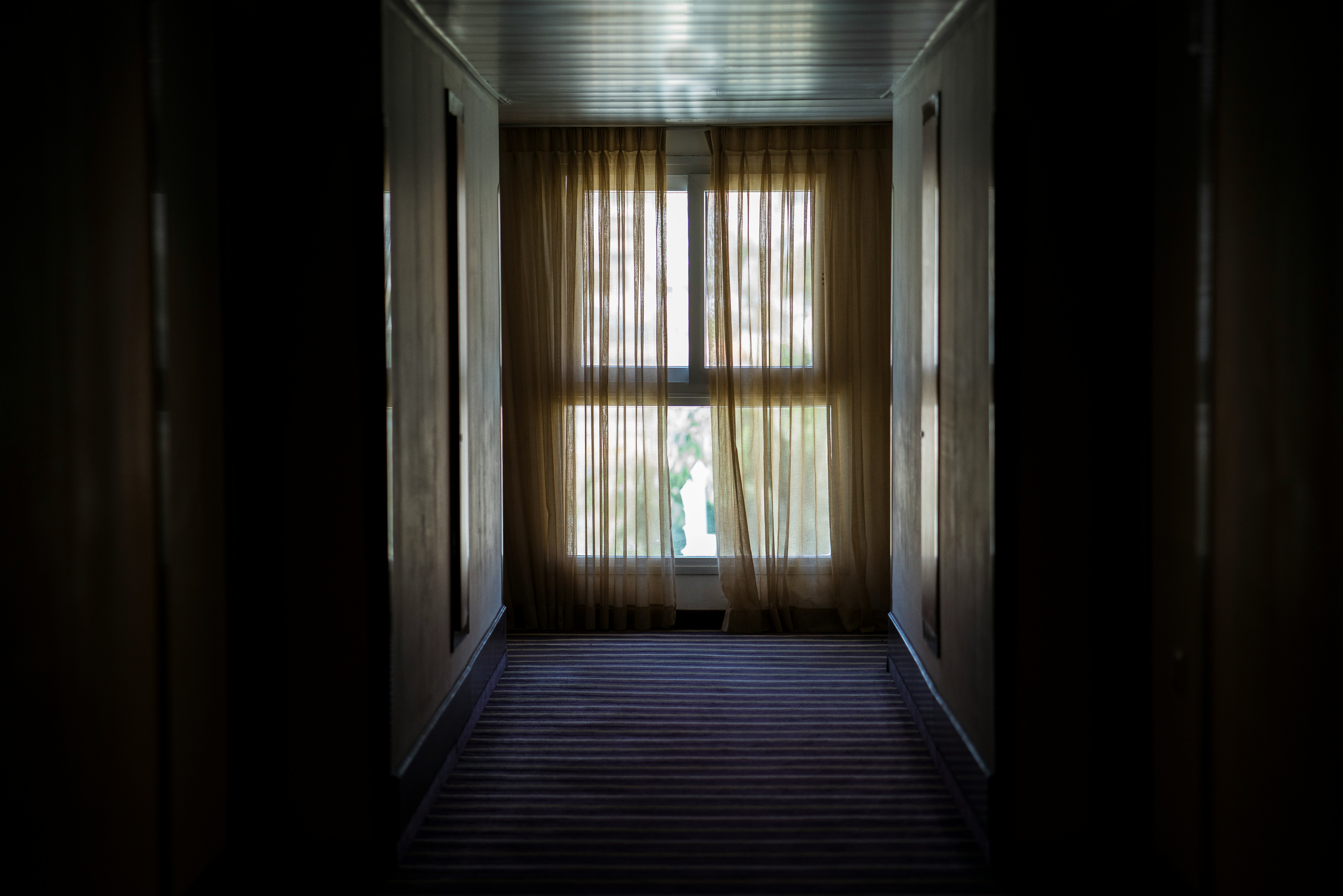 hallway leading to window covered by brown window curtain