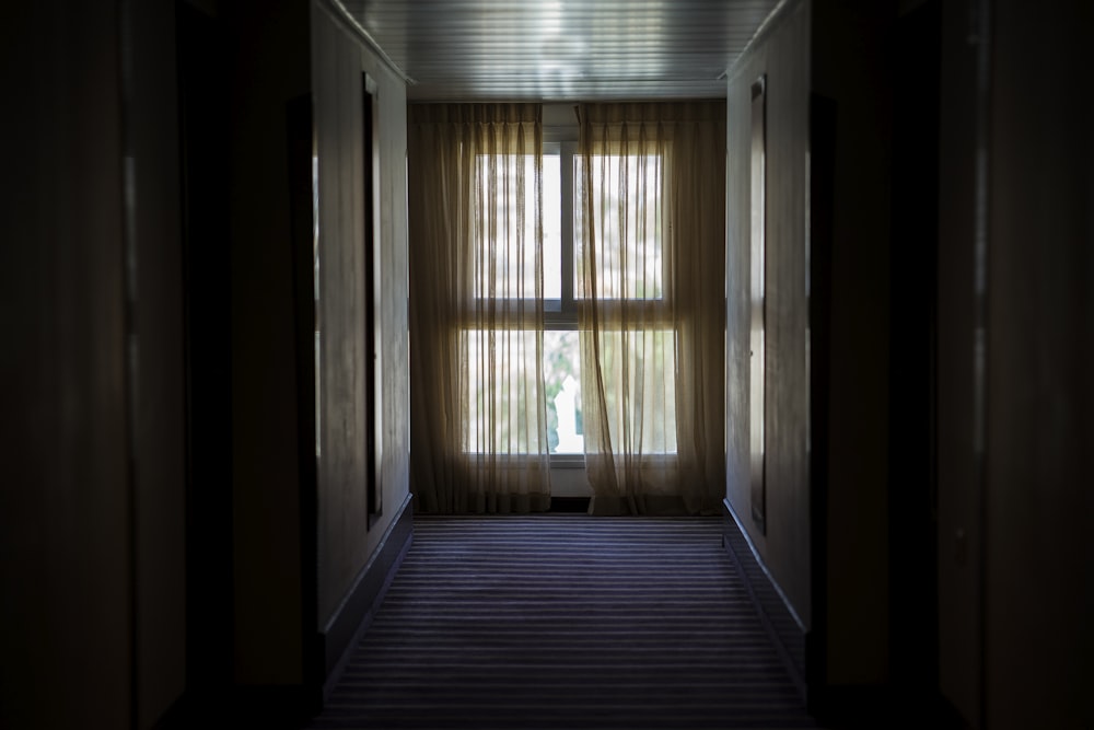 茶色の窓のカーテンで覆われた窓に通じる廊下
