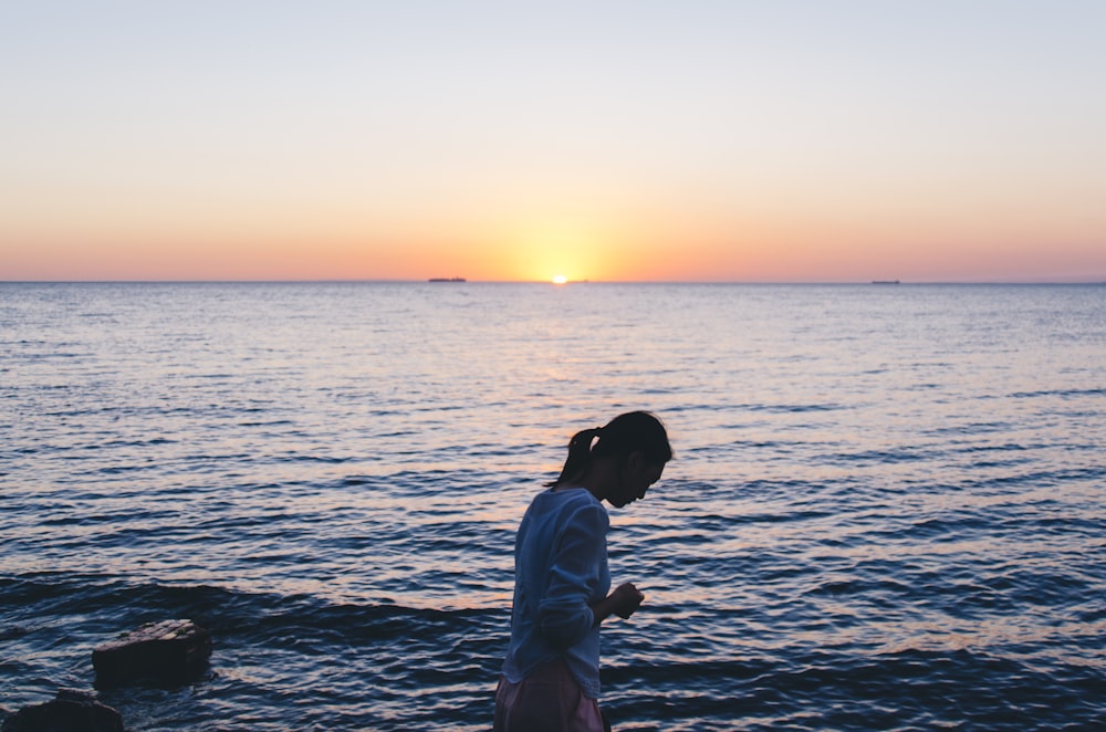 woman in blue long-sleeved shirt near body of water