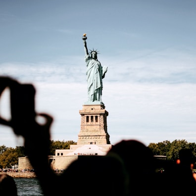 Travelers taking photos near a famous landmark in the United States with clear blue skies.