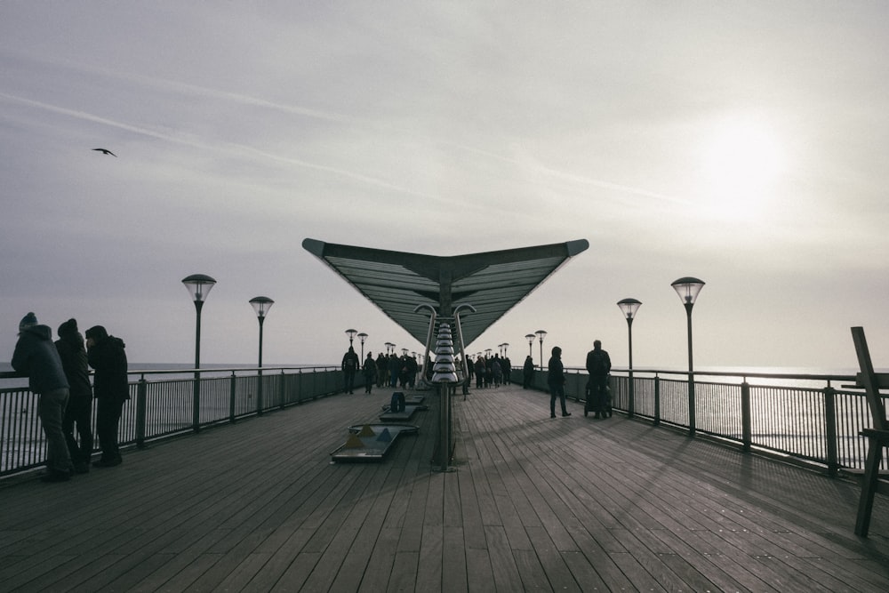 people on wooden dock with lampposts during day