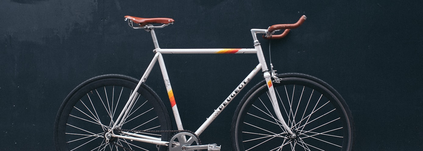 gray fixie bike leaning on black wall