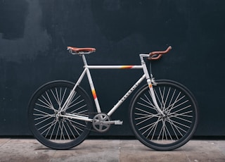 gray fixie bike leaning on black wall