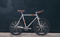 gray fixie bike leaning on black wall