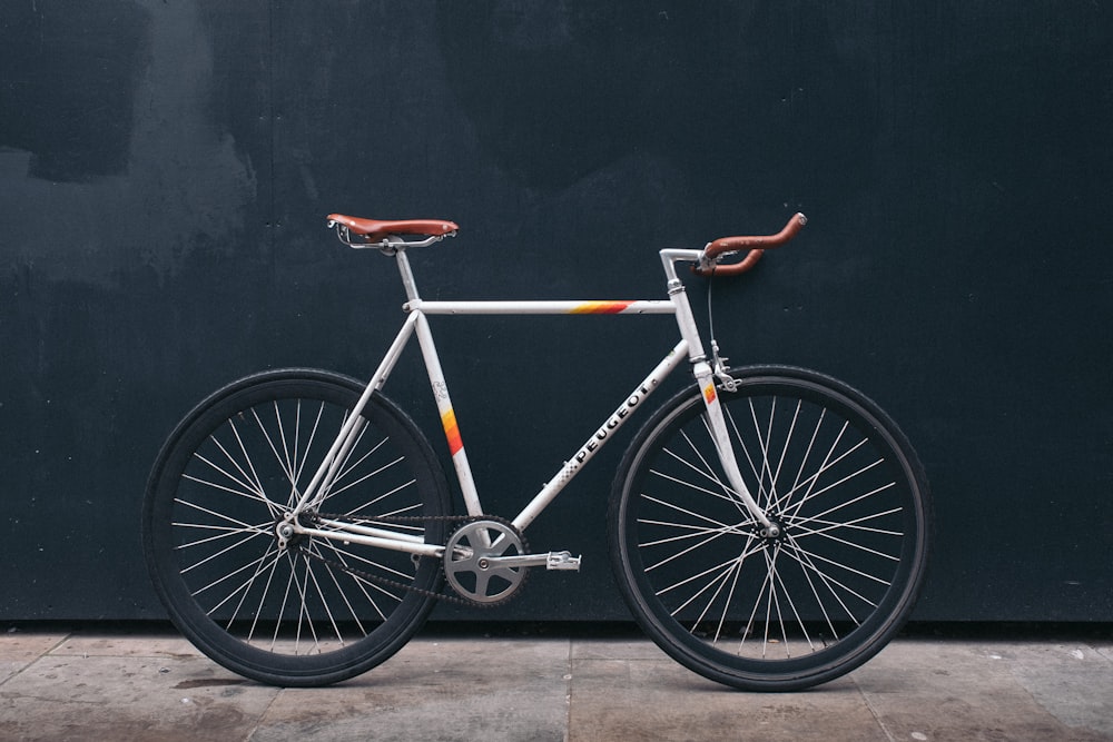 Bicicleta fixie gris apoyada en la pared negra