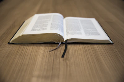 an open book on a cream-colored table with a muted terracotta bookmark peeking out