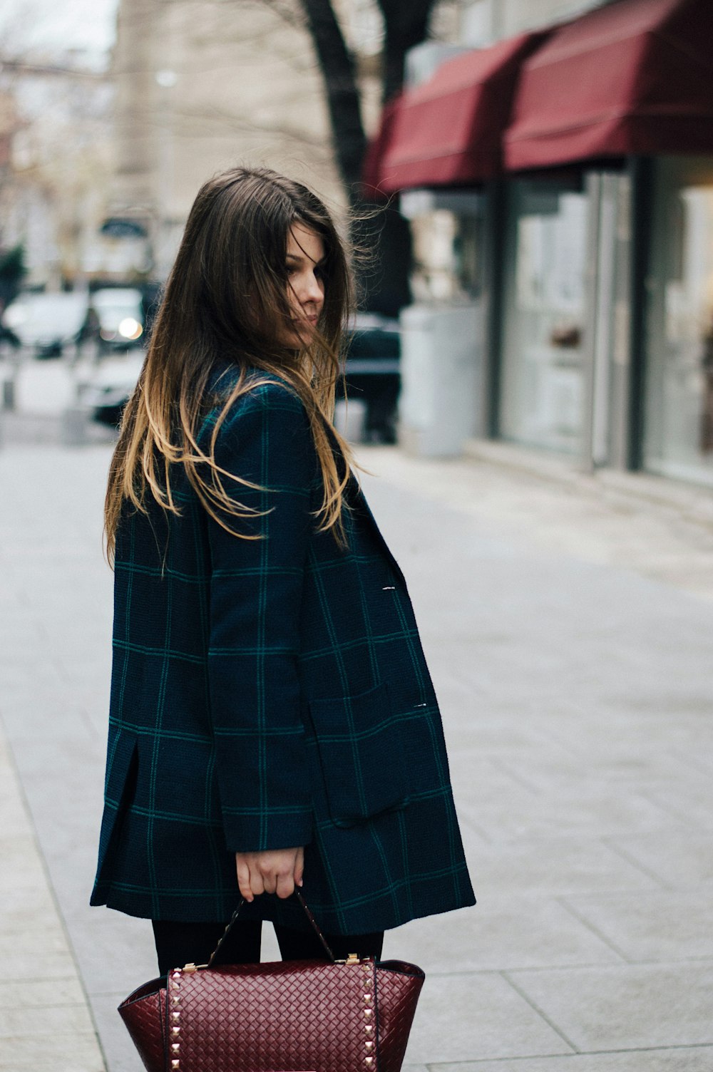 Mujer sosteniendo bolso de cuero marrón en fotografía bokeh