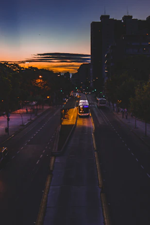 A modern city street at dusk with a Hello Ride car and bike waiting near a glowing bus stop.