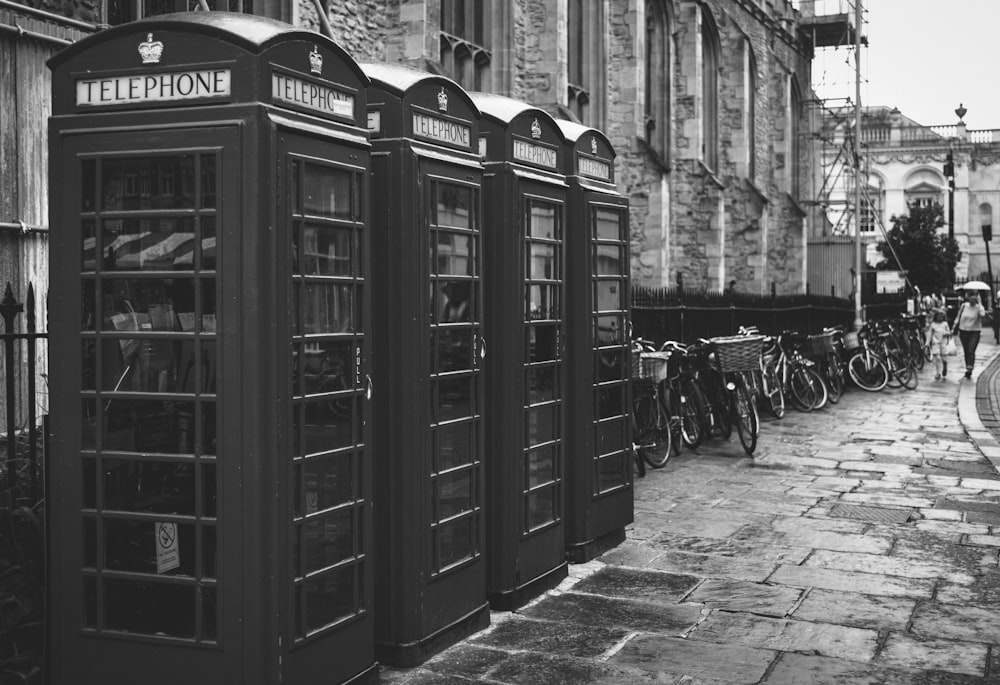 grayscale photo of four telephone booths lined up