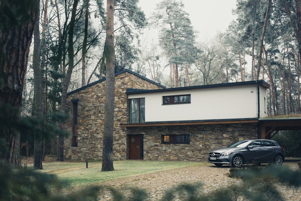 black SUV park beside white and brown house during daytime