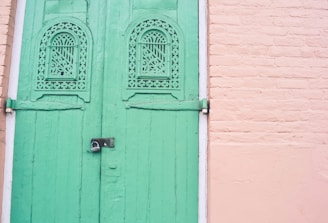 Modern steel door installed in a traditional Kerala-style home surrounded by lush greenery.