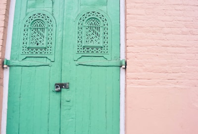 Modern steel door installed in a traditional Kerala-style home surrounded by lush greenery.