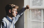 Professional looking out a window feeling disconnected from himself and his purpose