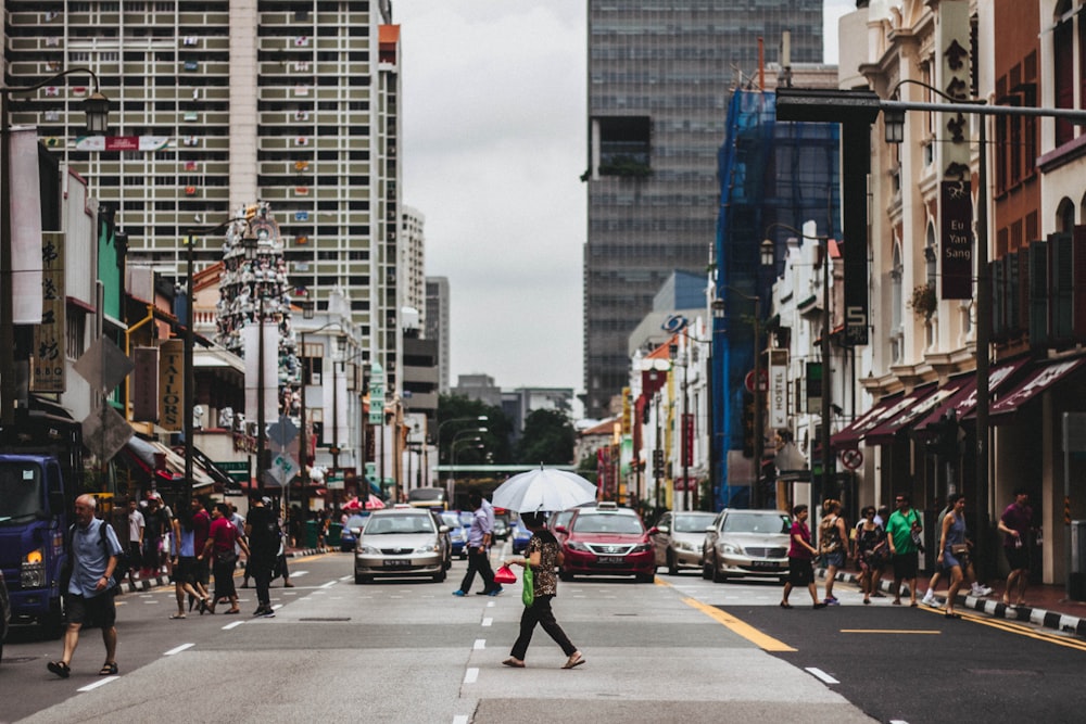 woman crossing road while holding umbrella