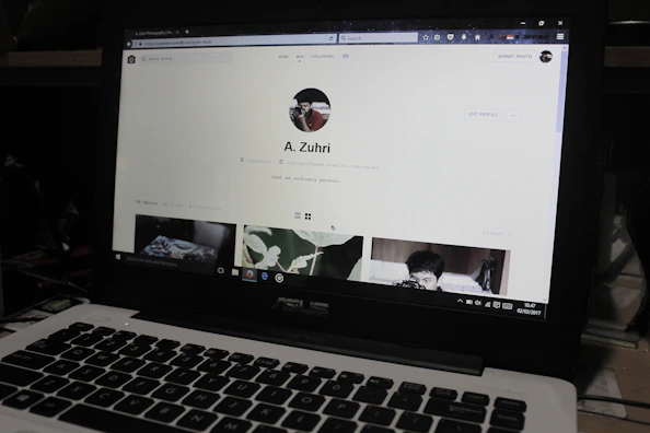 Social media manager working on a laptop with royal blue and grey branding elements visible.