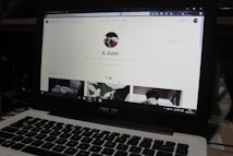 A laptop displaying a social media profile page with various elements such as a profile picture, username, and links. Below the main header, there are sections for photos and collections, showing preview images. The laptop keyboard is visible in the lower part of the image.