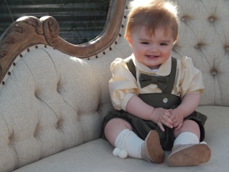 A toddler wearing a cozy corduroy outfit with a little bow tie and matching moccasins.