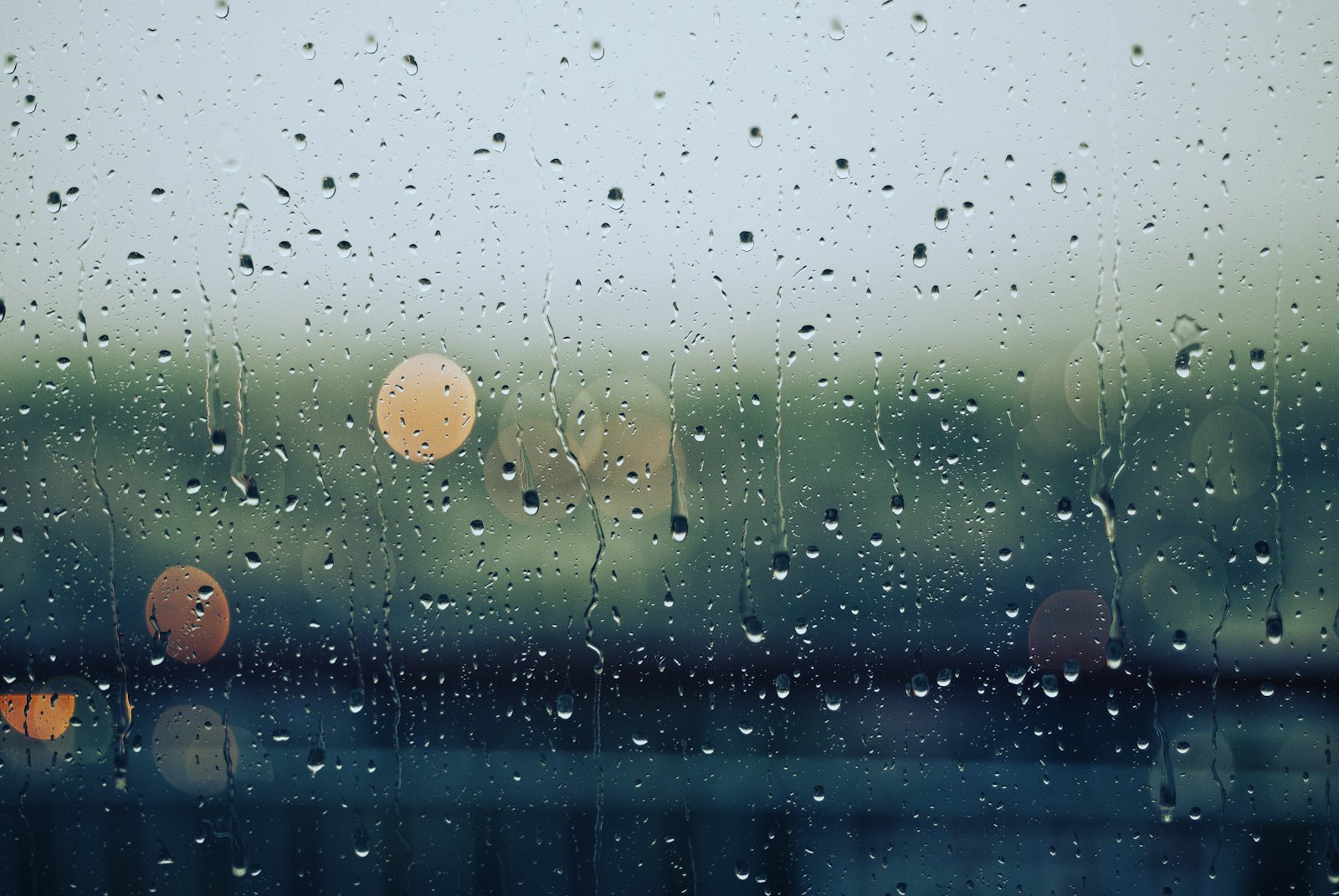 Window streaked with rain, Nordic coastal light blurred behind