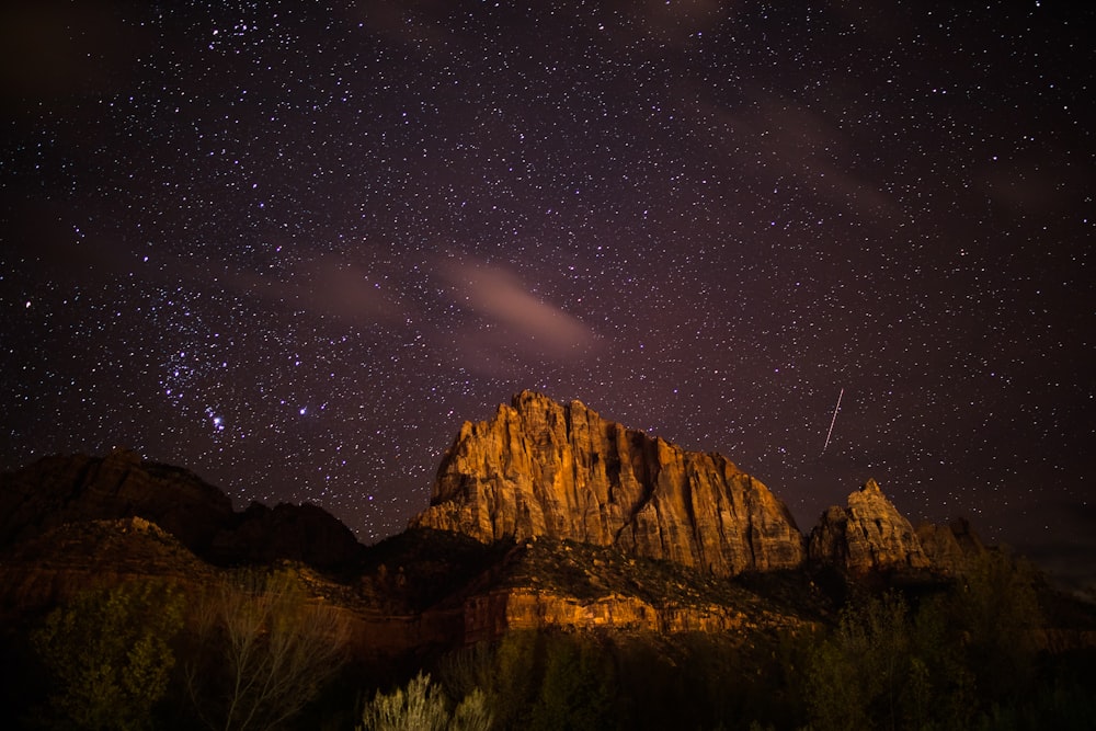 brown rocky mountain near body of water at night