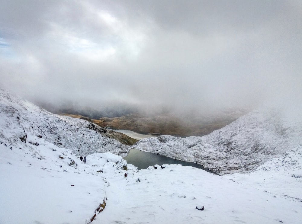 paisagem da montanha de neve com corpo de água e nevoeiro durante o dia