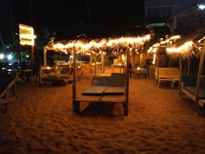 A candid moment of festival-goers relaxing on cozy lounge seating, bathed in soft warm sand lighting and good vibes.
