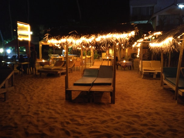Elegant lounge setup on the beach with plush cushions and soft lighting during golden hour.