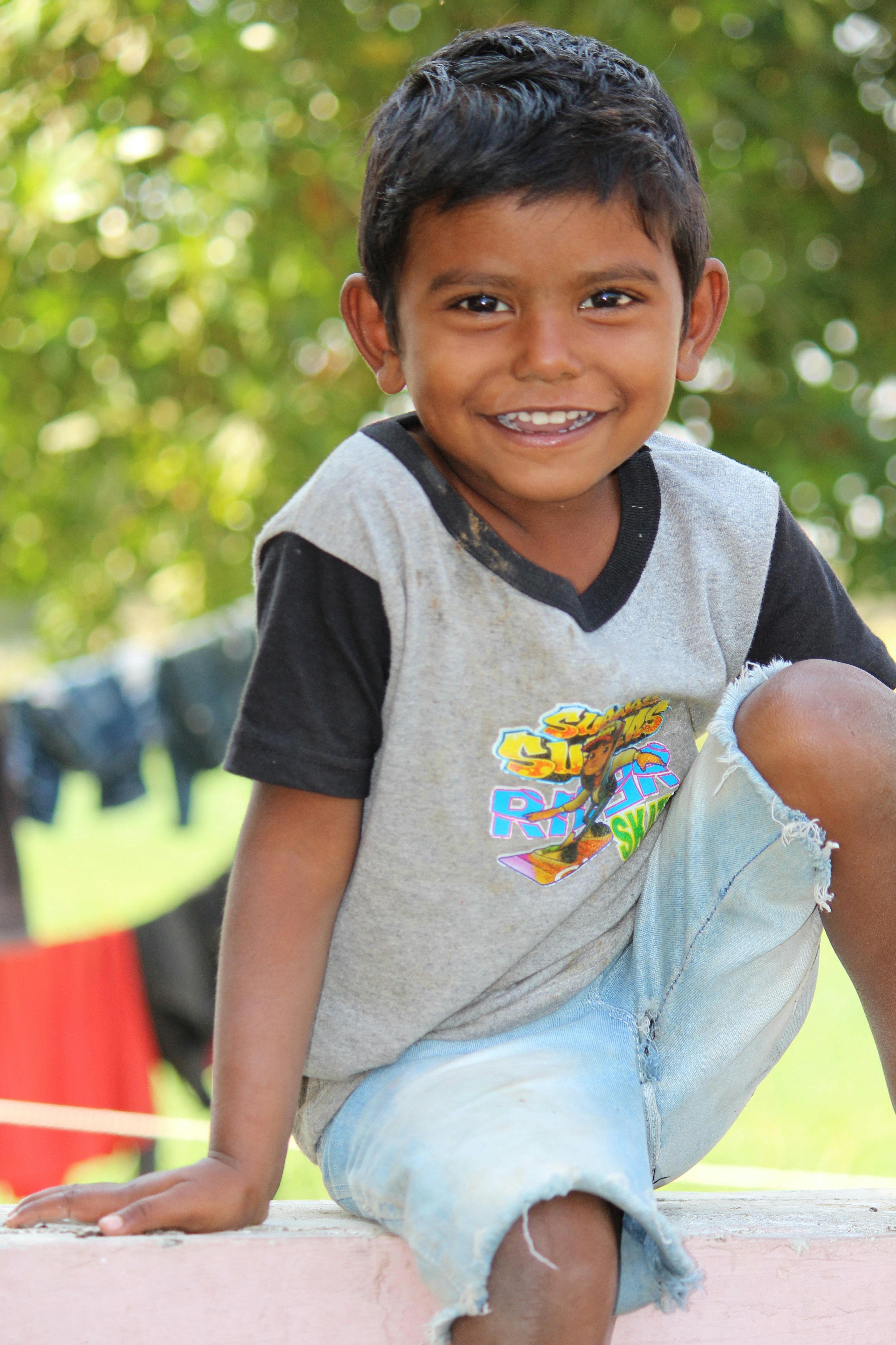 Young boy smiling widely outdoors, energetic and joyful, bright daylight