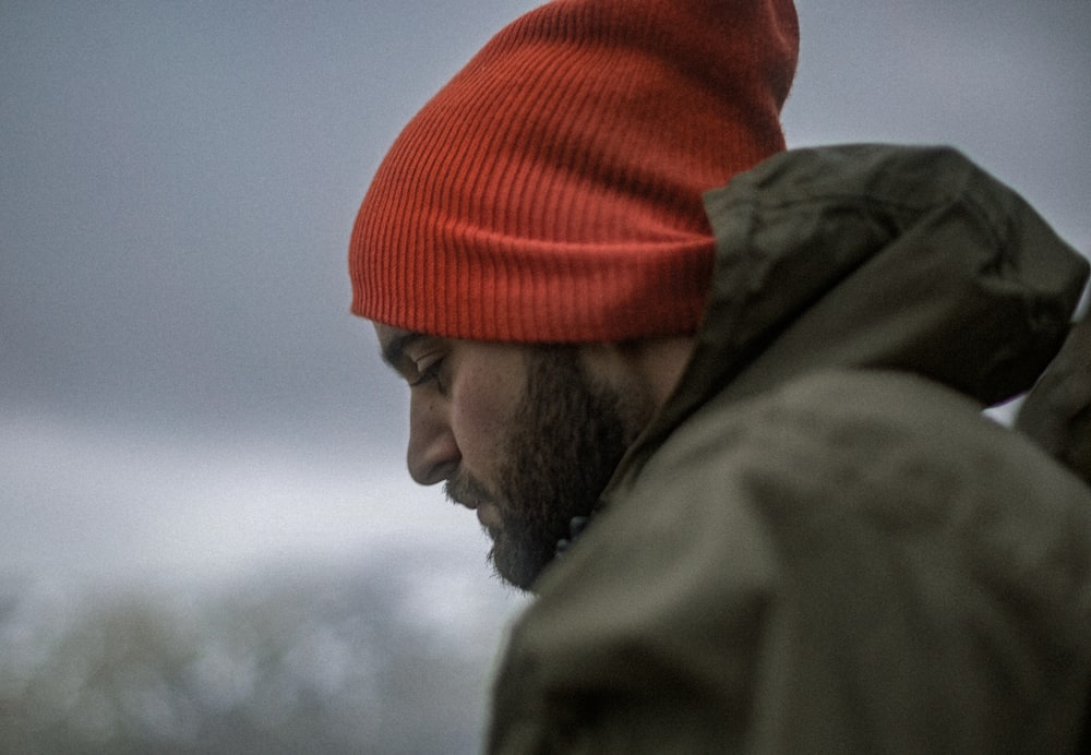 homme portant un sweat à capuche gris et une casquette en tricot orange