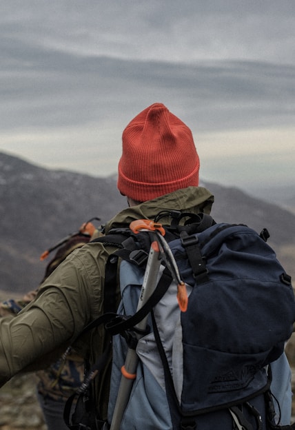 man in red beanie standing on cliff