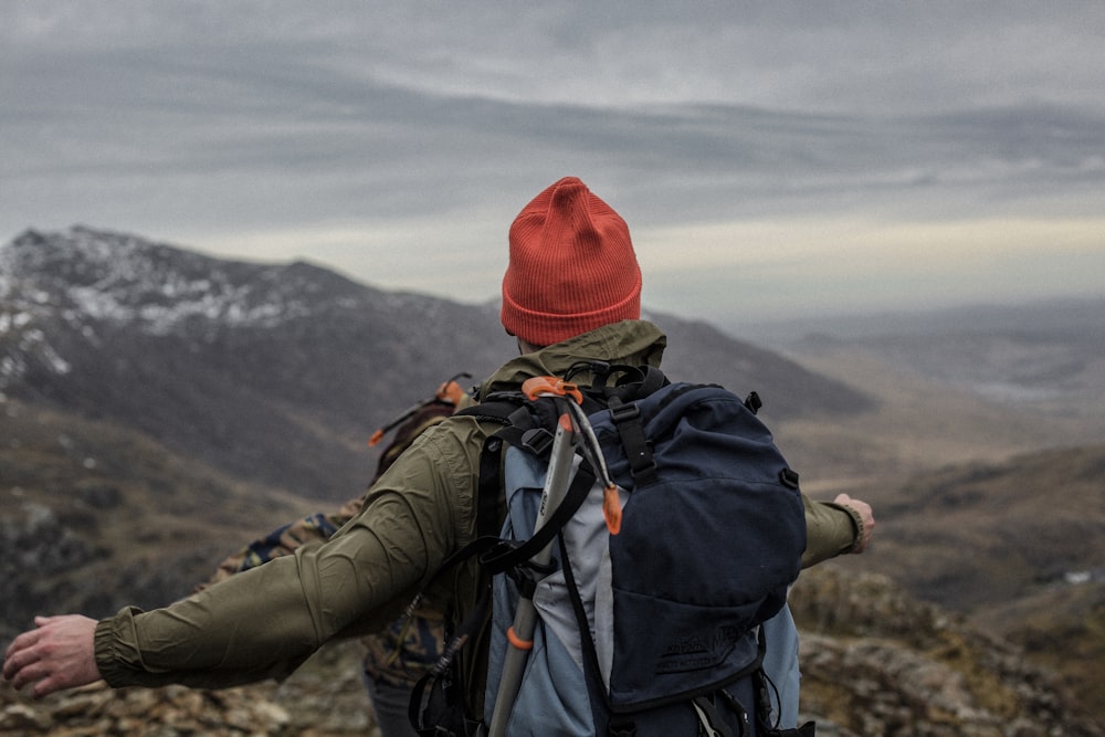 man in red beanie standing on cliff