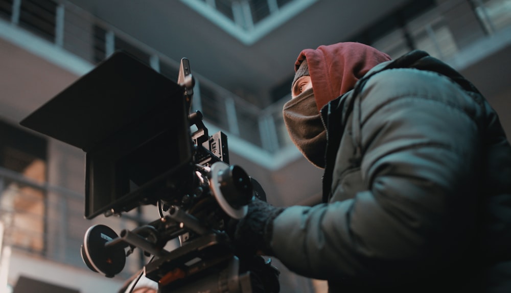 Fokusfotografie eines Mannes in schwarzer Jacke mit Kamera