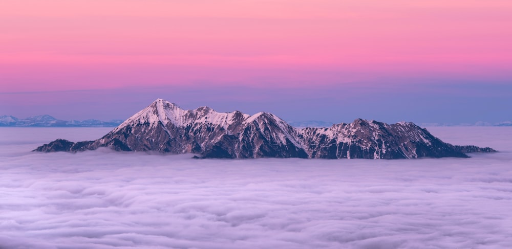 Foto de una montaña nevada rodeada de un mar de nubes