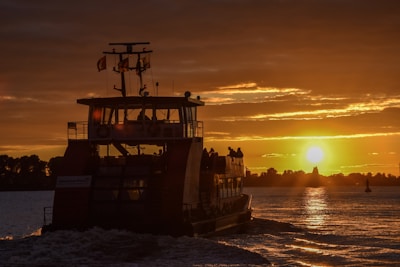Passengers boarding a ferry at sunset.