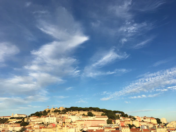 A panoramic view of Toledo's skyline featuring the Alcázar and the Tagus River under a clear blue sky.