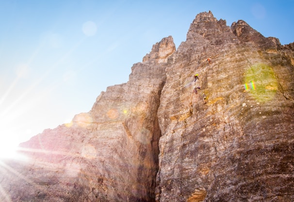 A group of climbers carefully navigating a rocky crag under clear blue skies.