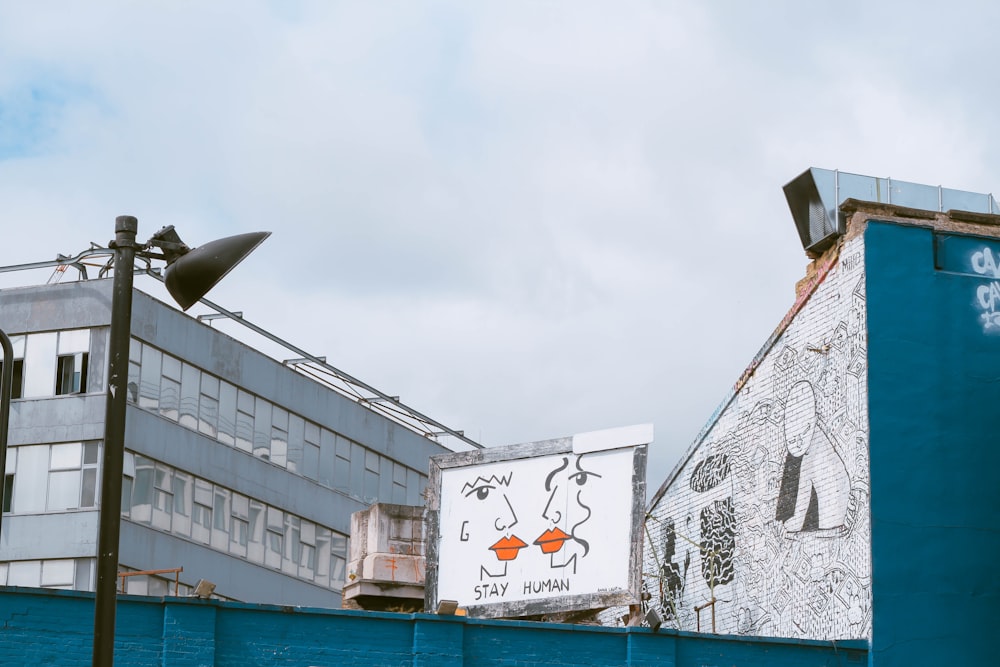 white and grey wooden billboard near white concrete building