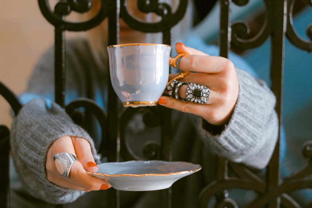 person holding teacup and saucer