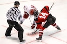 two persons playing ice hockey with referee