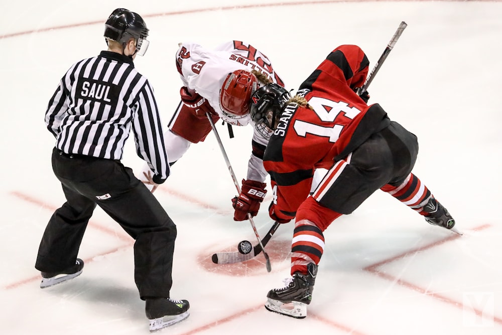 two persons playing ice hockey with referee