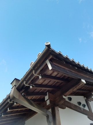 Elegant Caribbean villa roof structure showcasing robust teak beams under a clear blue sky.