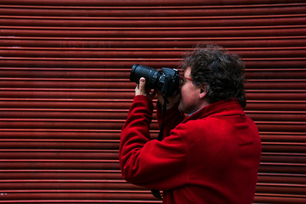 Man using a black DSLR camera to photograph a PTA event, illustrating the use of online sign-up tools for school activities.